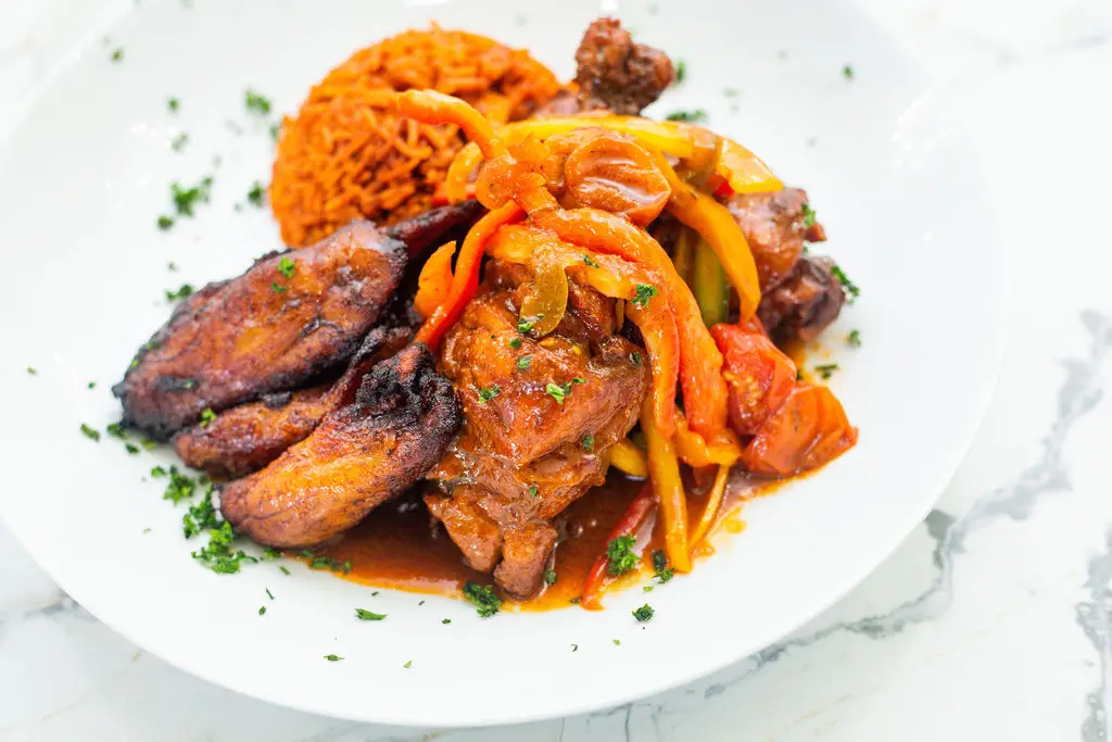 NIGERIAN STEW CHICKEN Tender chicken simmered in a rich, spicy tomato and pepper sauce served with Jollof rice and sweet plantain